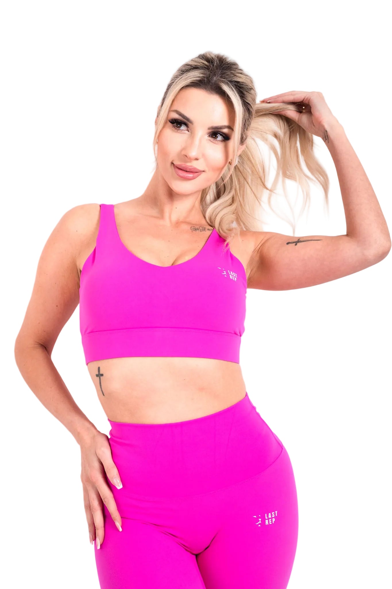 A person wearing a hot pink sports bra and matching high-waisted leggings, posing with one hand raised to their head.