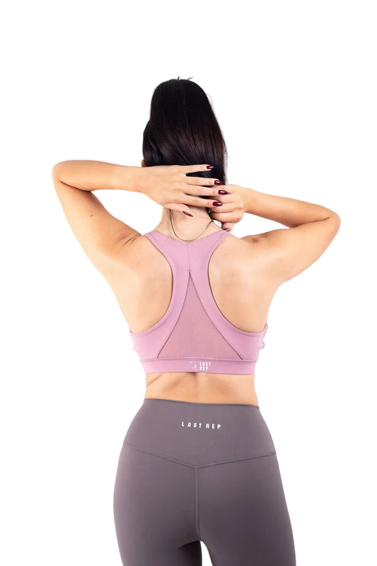 Person wearing a pink sports bra and gray leggings with 'Gaiam' branding on a gray background