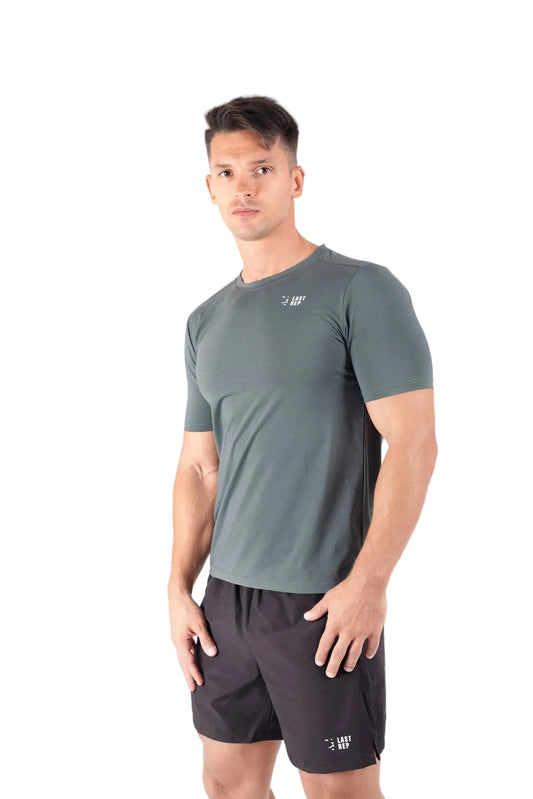Man wearing a gray athletic shirt and black shorts on a gray background