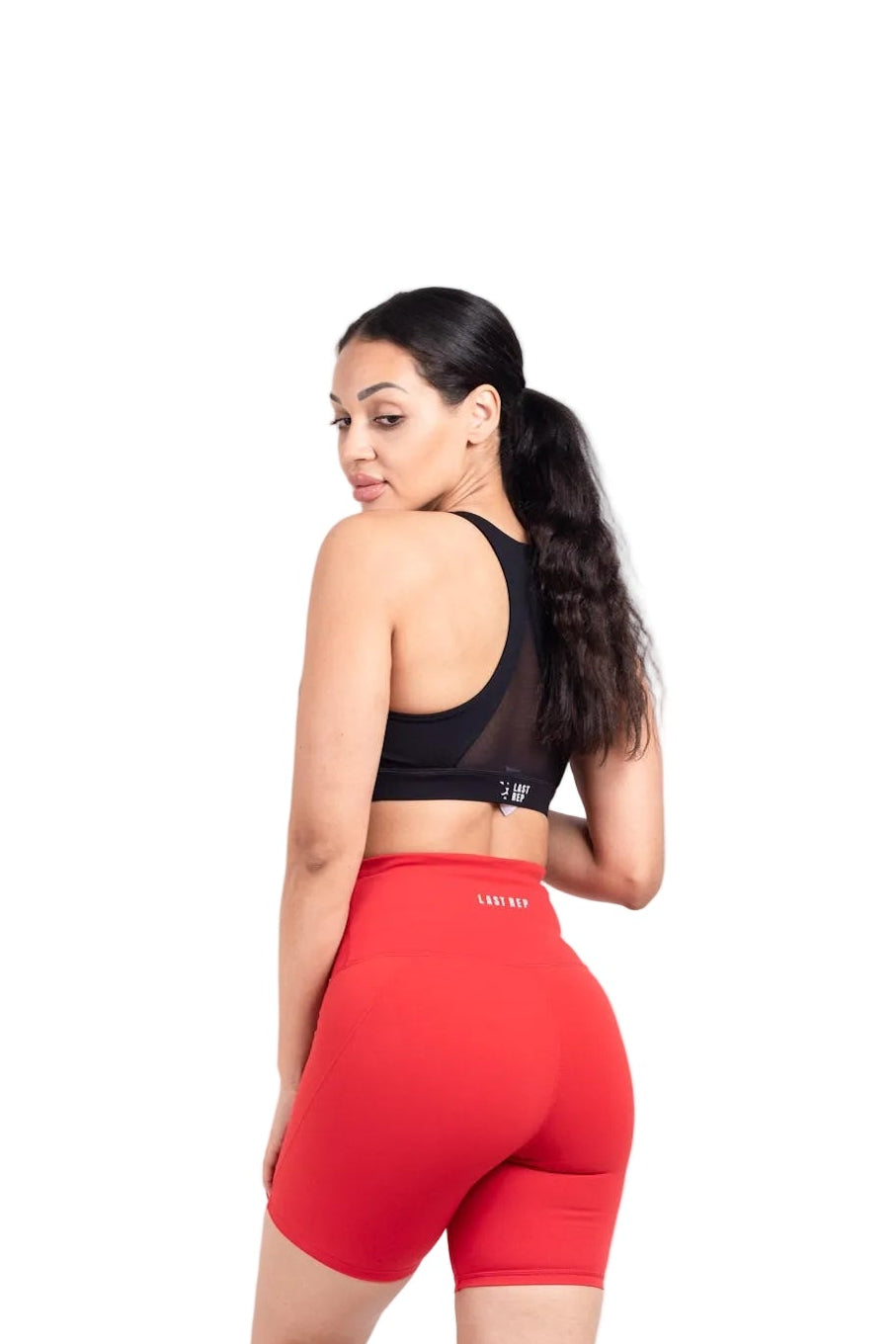 Woman wearing a black sports bra and red shorts on a white background
