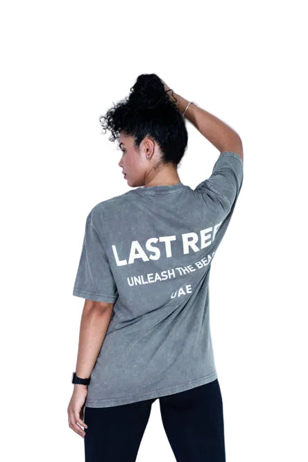 Person wearing a gray t-shirt with text on the back, standing against a white background