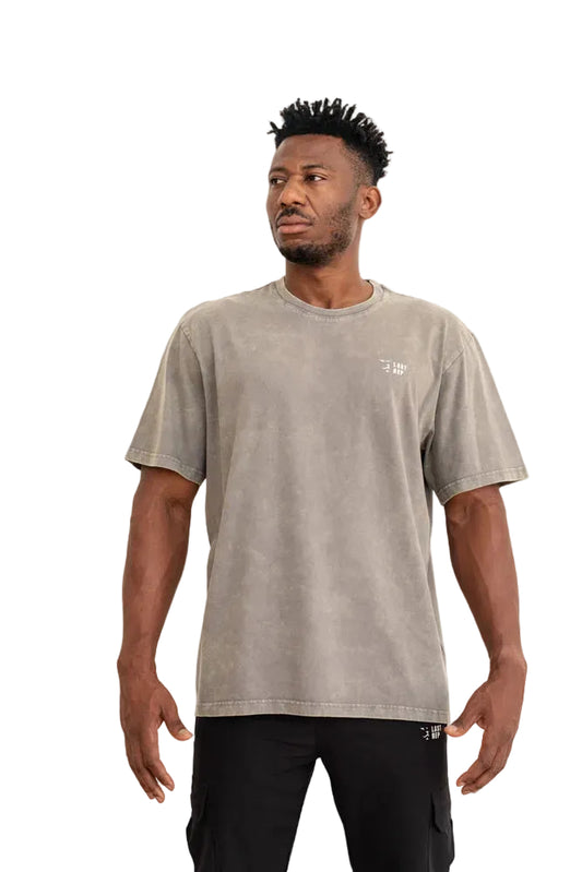 Man wearing a beige t-shirt with a logo on a gray background